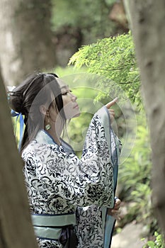 Asian Chinese woman in traditional Blue and white Hanfu dress, play in a famous garden ,Stand under the maple tree