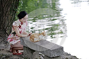 Asian Chinese woman in traditional cheongsam play with a cat photo