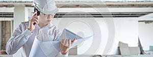 Asian engineer man using phone while reading blueprints