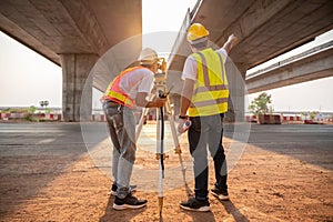 Asian civil engineer and surveyor engineers making measuring and pointing finger under the expressway with theodolite on road