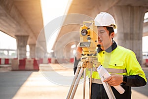 Asian civil engineer or surveyor making measuring under the expressway with theodolite on road works. Survey engineer at road