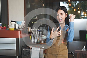 Asian Coffee Shop Owner Accepts a Pre-Order on a Tablet Smiling to the Customer in a Cozy Cafe. Restaurant Manager Browsing