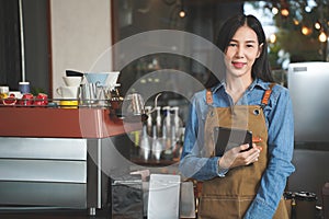 Asian Coffee Shop Owner Accepts a Pre-Order on a Tablet Smiling to the Customer in a Cozy Cafe. Restaurant Manager Browsing