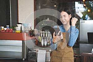 Asian Coffee Shop Owner Accepts a Pre-Order on a Tablet Smiling to the Customer in a Cozy Cafe. Restaurant Manager Browsing