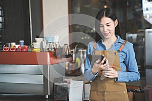 Asian Coffee Shop Owner Accepts a Pre-Order on a Tablet Smiling to the Customer in a Cozy Cafe. Restaurant Manager Browsing