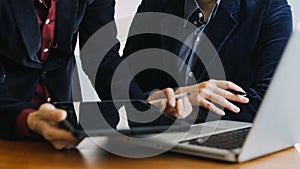 Asian colleagues man and woman discussing and working with laptop computer on office desk in the office