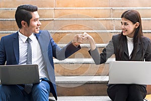 Asian colleagues team success concepts, Businessman and businesswoman looking at each other and doing fist bump celebrate.