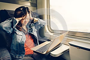 Asian college girl frustrated with laptop on the train, warm light tone, with copy space