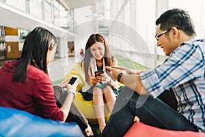 Asian college students or coworkers using smartphones together. Fun modern lifestyle, social network