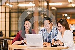 Asian college students group or coworkers using laptop computer together at cafe or university. Casual business, freelance work photo