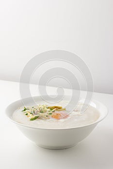 Asian congee with minced pork and egg in bowl.