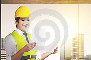 Asian construction worker with hardhat holding planning paper