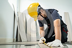 Asian Construction worker installs laminate board on floor in house. Craftsman builder or Carpenter male wear work safety helmet,