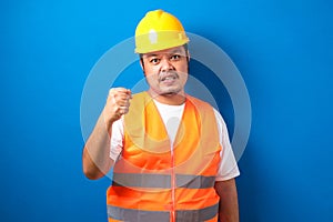 Asian construction worker man wearing orange vest and safety helmet with clenched fist