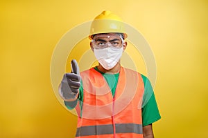 Asian construction worker pointing at his protective mask and savety helmet