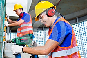 Asian construction workers drilling in building walls