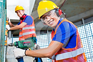 Asian construction workers drilling in building walls