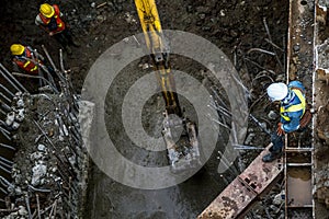 Asian construction workers laborers and excavator backhoe working for footing foundation on site of new route sky train