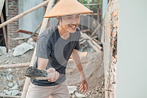 Asian construction workers use a cap using a scoop to attach cement to the bricks