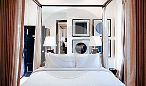 Asian contemporary hotel bedroom with four poster bed, white curtain, pillows and vintage lamps