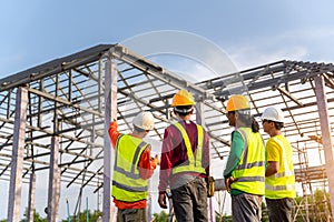 Asian Contractor with workers and Steel roof structure under construction background. Teamwork Concept