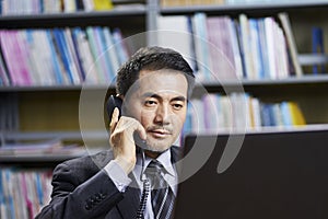 Asian corporate executive working in office talking on phone