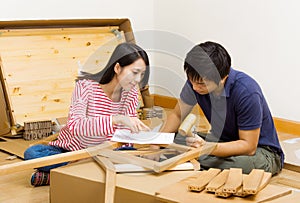 Asian couple assembling new furniture