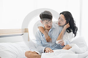 Asian couple on bed, woman blindfolded boyfriend