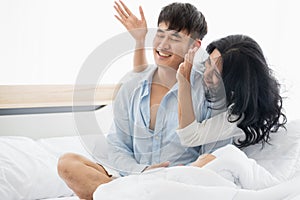 Asian couple on bed, woman blindfolded boyfriend