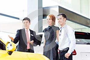 Asian couple buying car in dealership