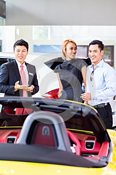 Asian couple buying car in dealership