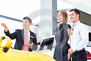 Asian couple buying car in dealership