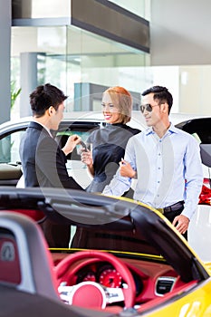 Asian couple buying car in dealership