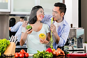 Asian couple cooking food together in kitchen