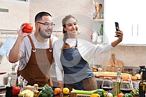 Asian couple cooking in kitchen making healthy food together feeling fun and using smartphone to take selfies