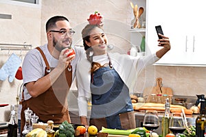 Asian couple cooking in kitchen making healthy food together feeling fun and using smartphone to take selfies
