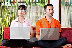 Asian couple on the couch with a laptop