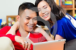 Asian couple on the couch with a tablet pc