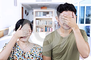 Asian couple cover faces at home