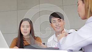 Asian couple discussing house purchases and information with project salespeople.