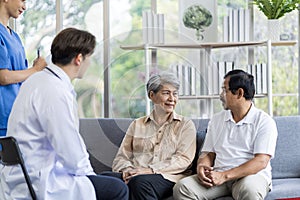 Asian couple Elderly men and women sit on sofas having fun and having fun talking with doctors who come to check their health at