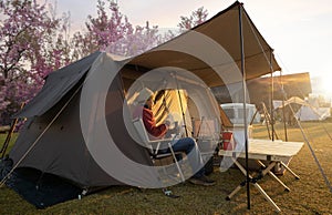 Asian couple enjoy in they tent in camping trip on night time with table, cup, mug and party inside tent, they enjoy coffee