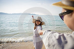 Asian couple enjoying beach vacation on beach, Smiling girlfriend walking with holding hand of her boyfriend on the beach in sumer