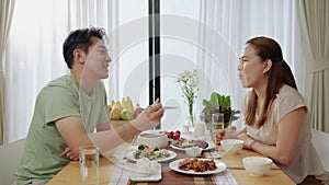 Asian couple feeding with chopsticks on table in their home, family relationship concept