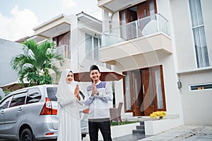 Asian couple with hand gestures wishing a happy Eid