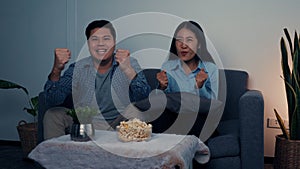 Asian couple has fun cheering on the soccer team competing on TV