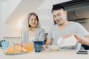 Asian couple having breakfast, cereal in milk, bread and drinking orange juice after wake up in the morning.