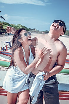 Asian couple having fun on the beach of tropical Bali island, Indonesia.