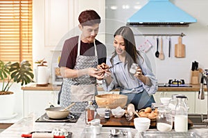 Asian couple Help each other to make a bakery In a romantic atmosphere in the kitchen at home. Young people work together to mix