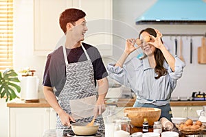 Asian couple Help each other to make a bakery In a romantic atmosphere in the kitchen at home. Young women help cook holiday with